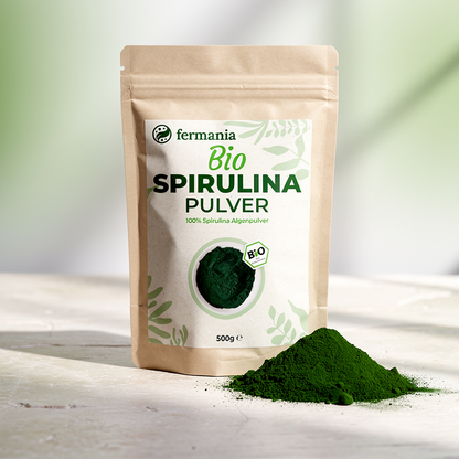 Spirulina Pulver Packung auf einer Marmorplatte mit einem Häufchen Spirulina Pulver